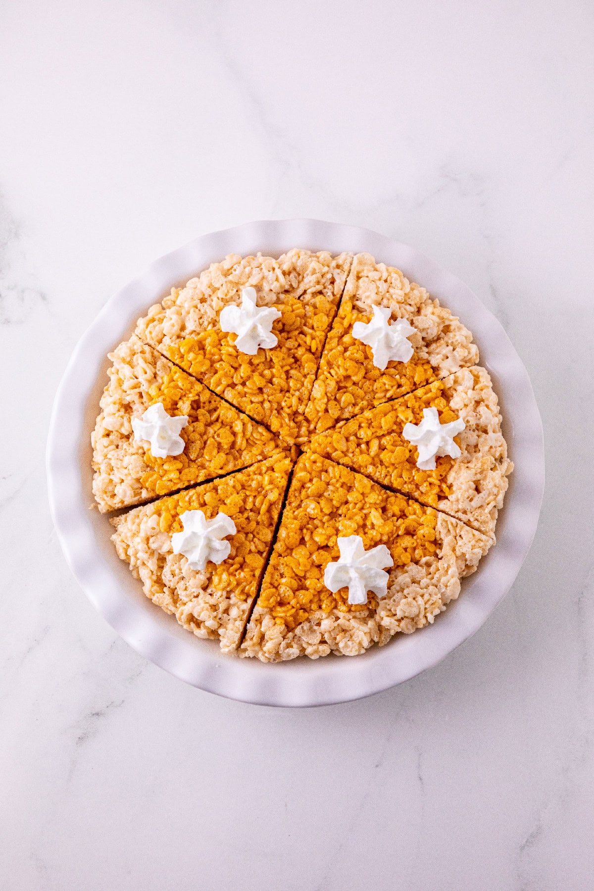 Pumpkin spice Rice Krispie pie cut into slices and topped with whipped cream.