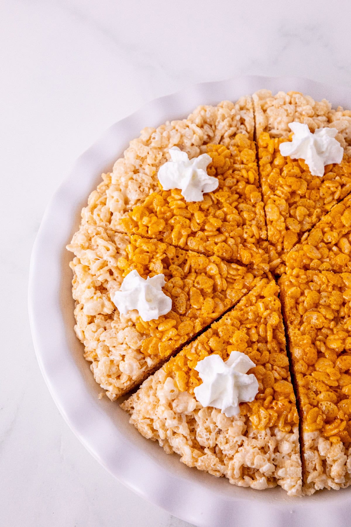 Close-up of pumpkin spice Rice Krispie pie slices topped with whipped cream.