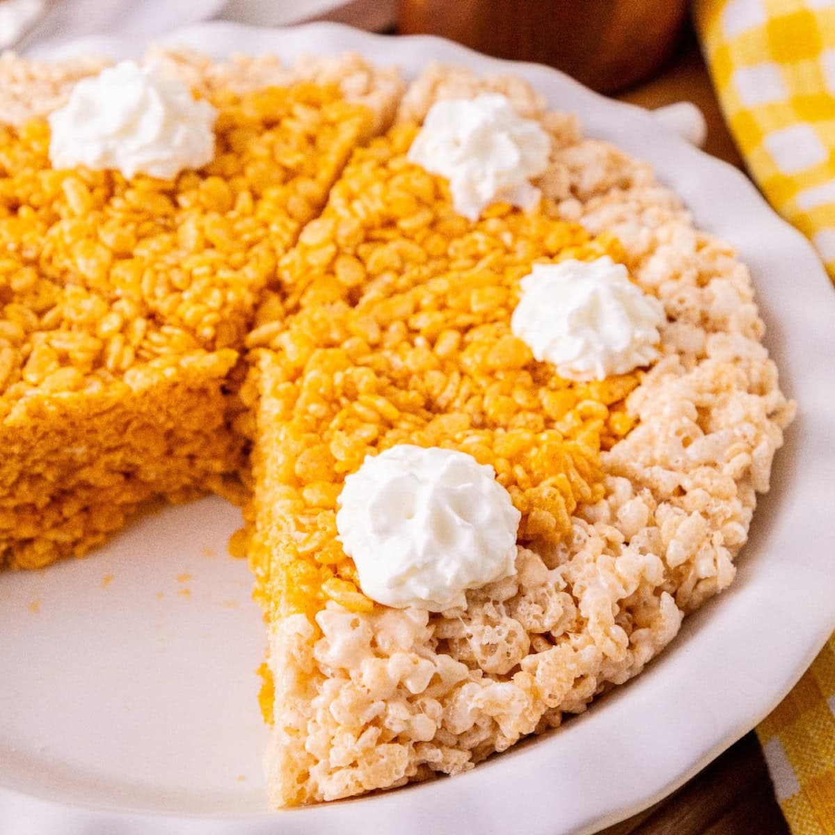 Pumpkin spice Rice Krispie treats shaped like pie slices and topped with whipped cream.