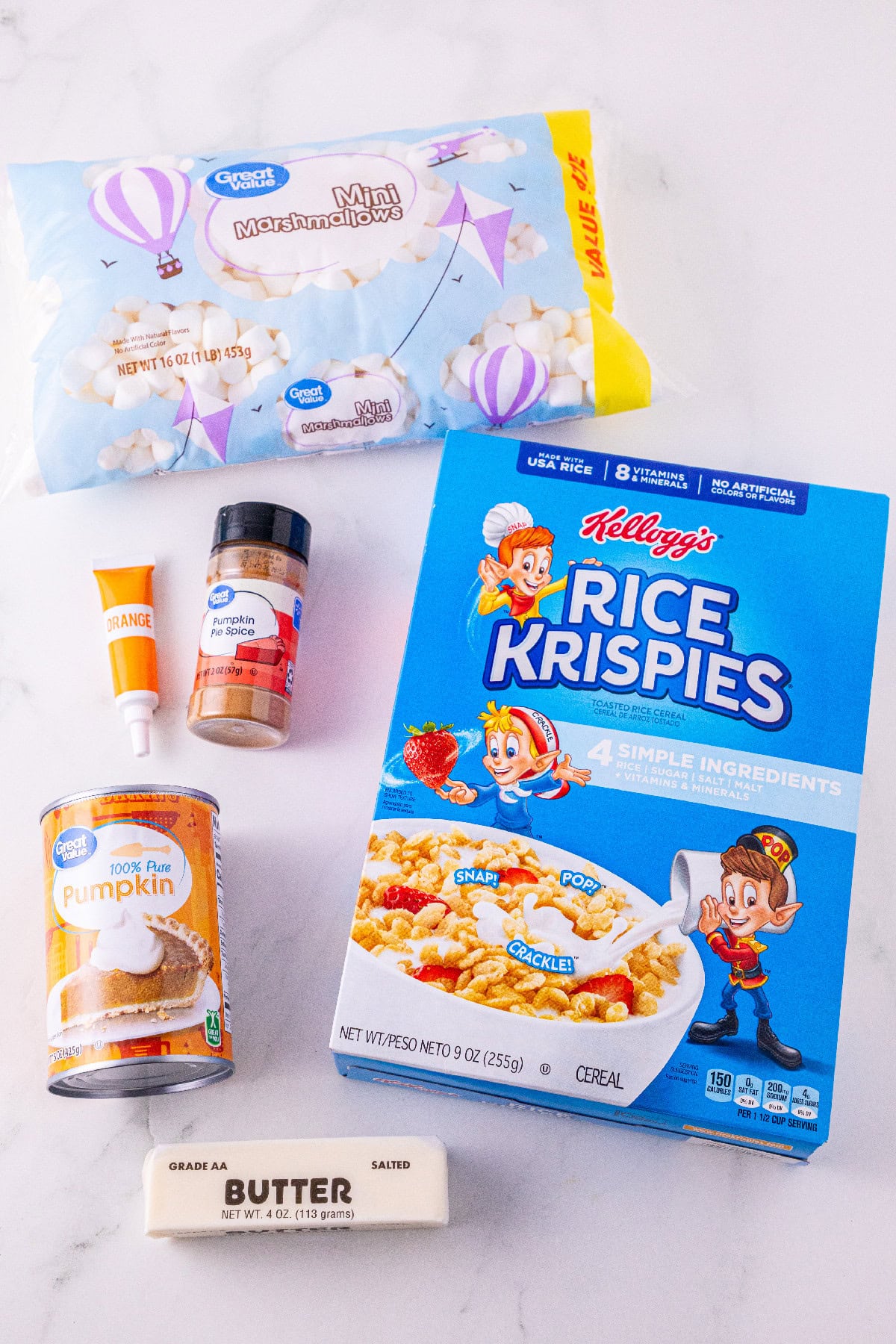 Ingredients for pumpkin spice Rice Krispie treats, including cereal, marshmallows, pumpkin puree, butter, pumpkin pie spice, and orange food coloring.