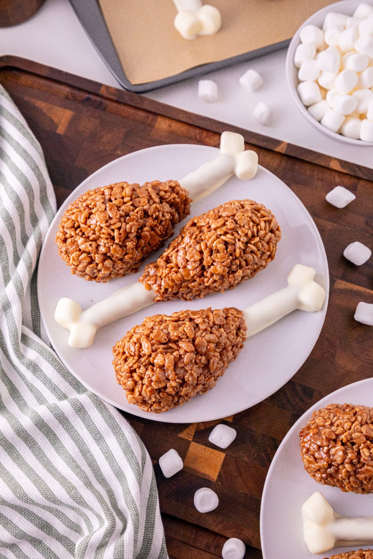 Rice Krispie turkey leg treats with white chocolate pretzel bones arranged on a plate.