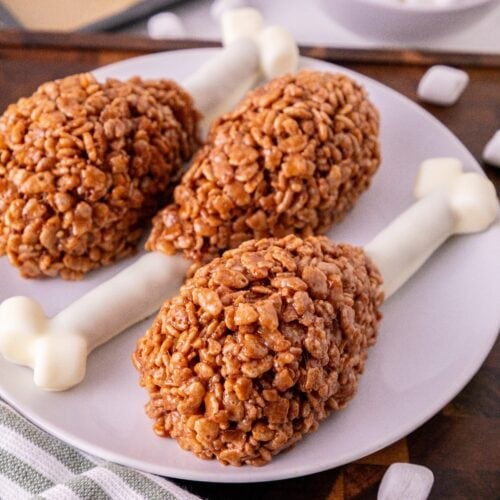 Rice Krispie turkey leg treats with white chocolate pretzel bones arranged on a plate.