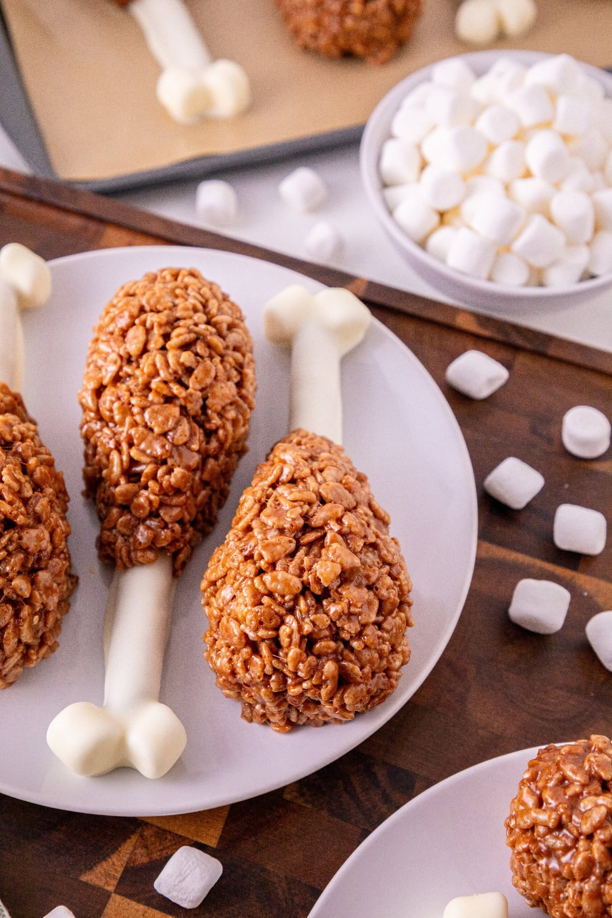 Three Rice Krispie turkey leg treats arranged beside mini marshmallows.