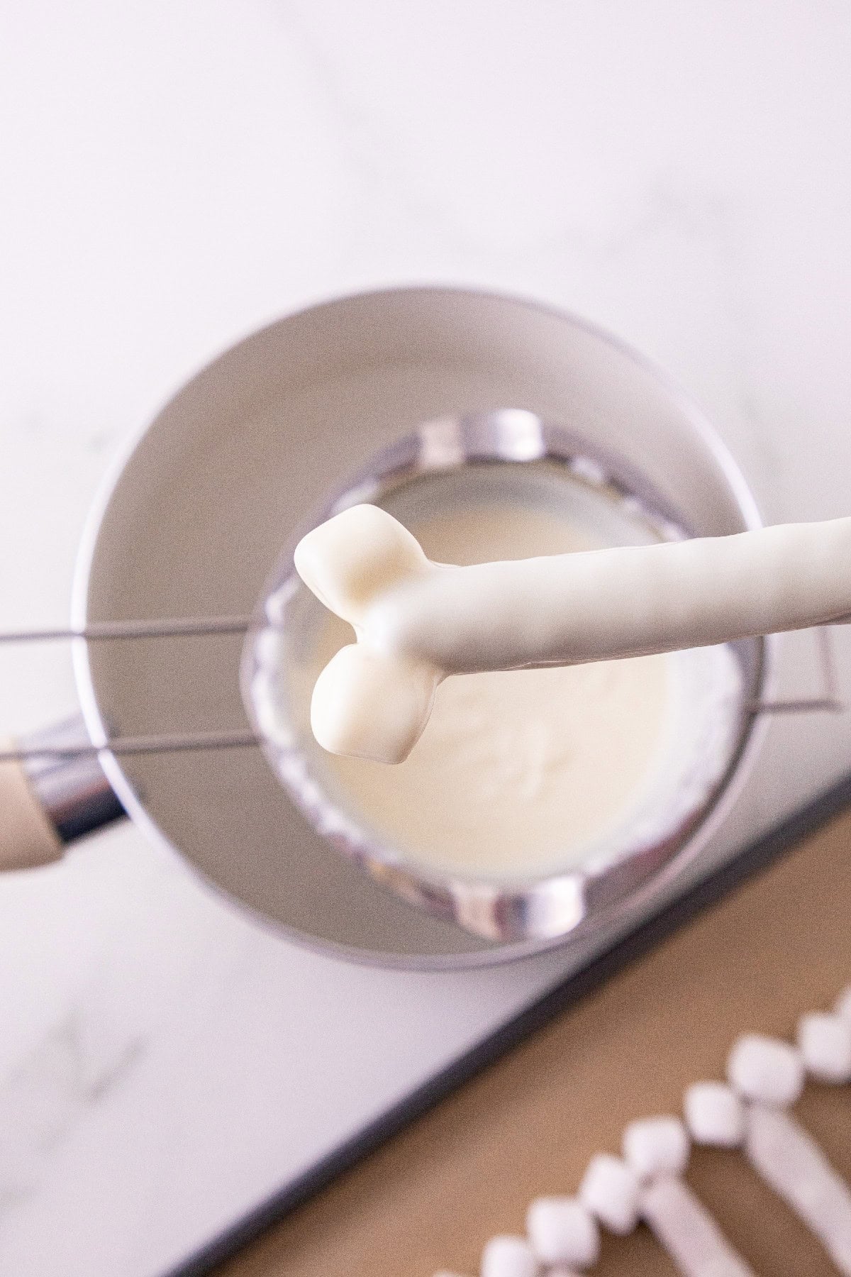 Pretzel rod and marshmallows coated in melted white wafers.