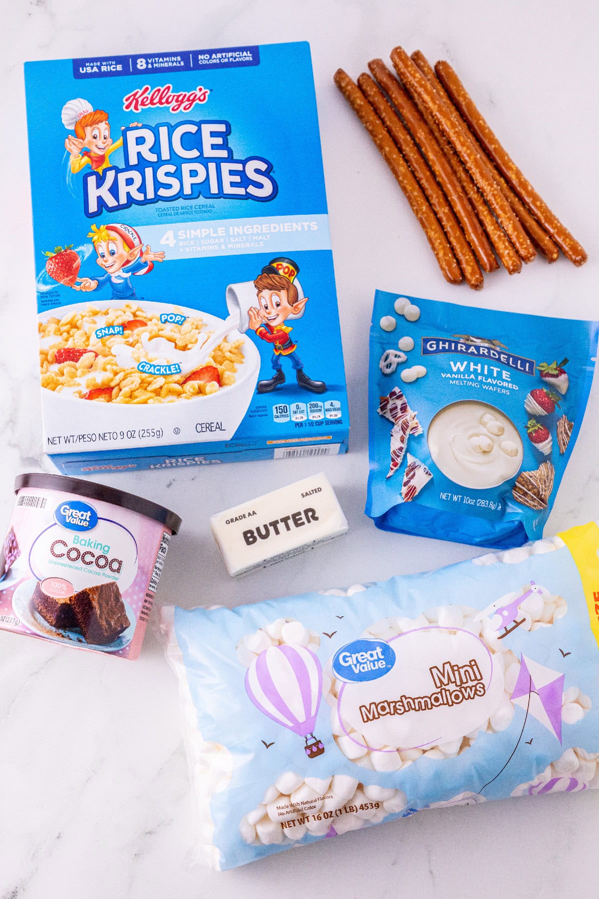 Ingredients for Rice Krispie turkey leg treats, including cereal, pretzel rods, marshmallows, butter, cocoa powder, and white melting wafers.