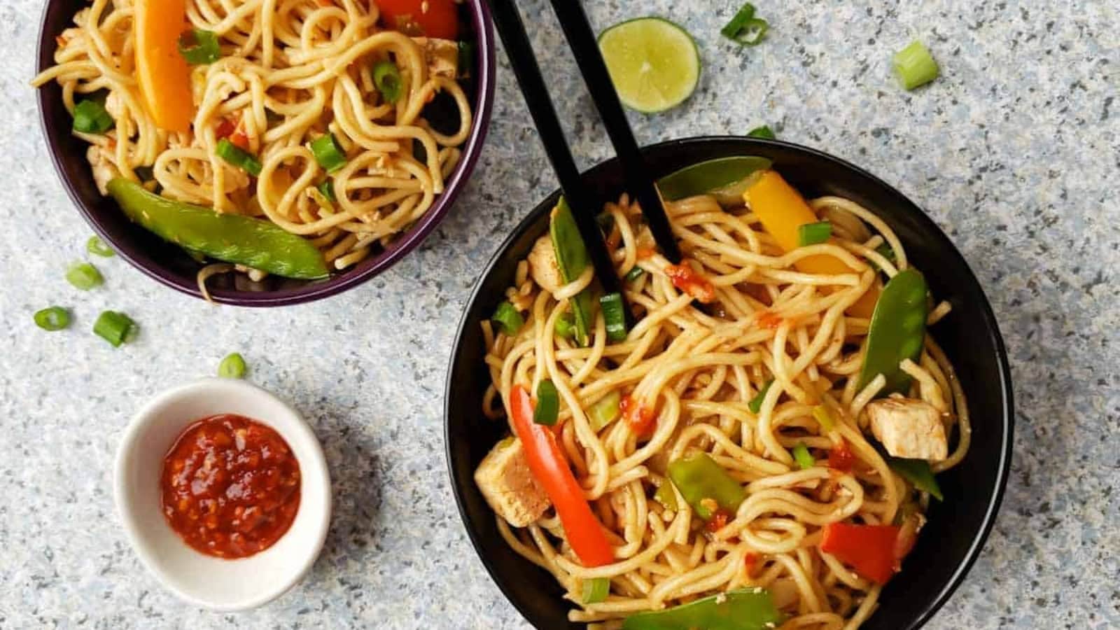 Chinese noodles tossed with spicy chili garlic sauce and fresh garnishes.