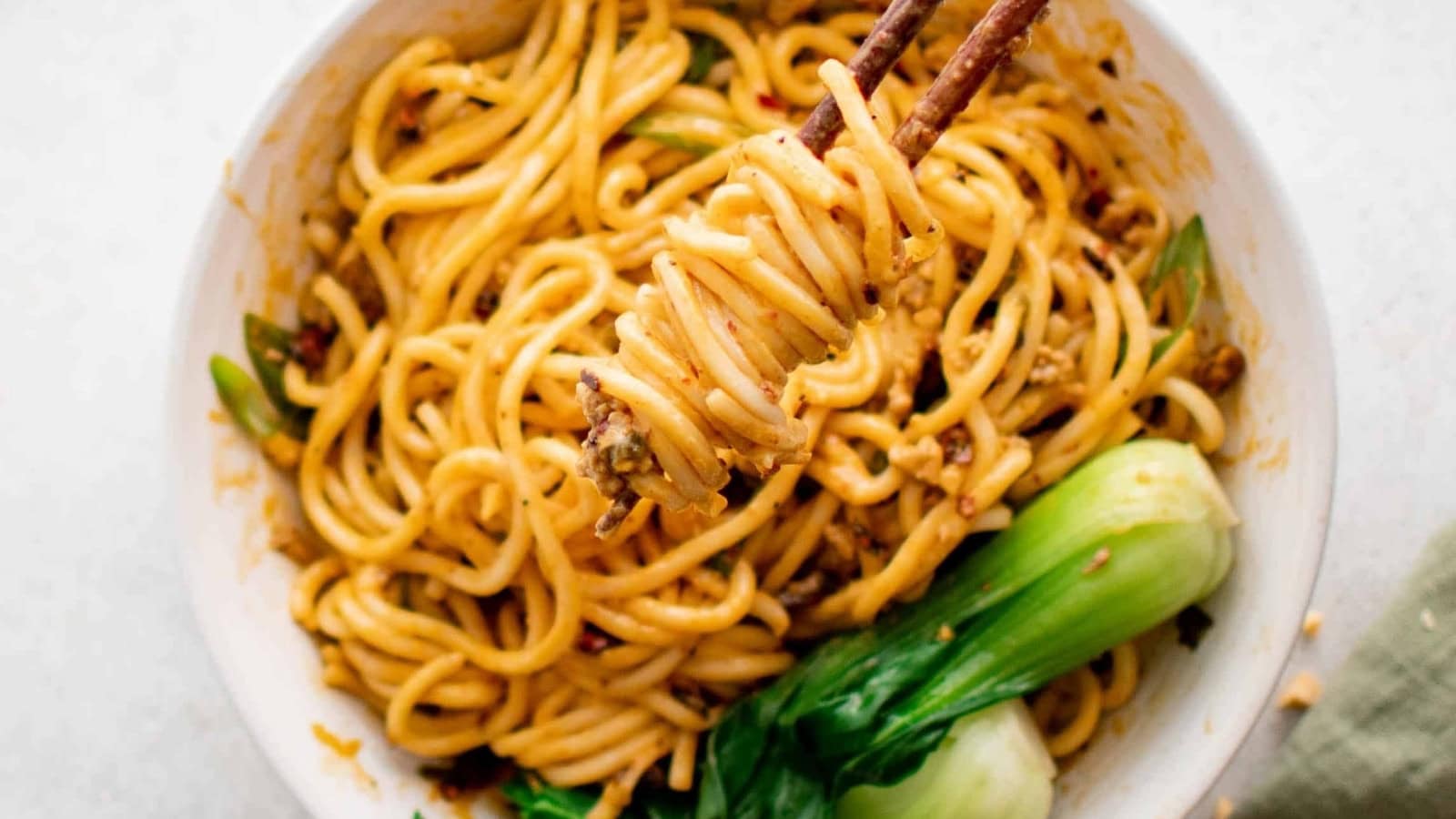 Spicy Dan Dan noodles topped with savory sauce, aromatics, and garnishes.