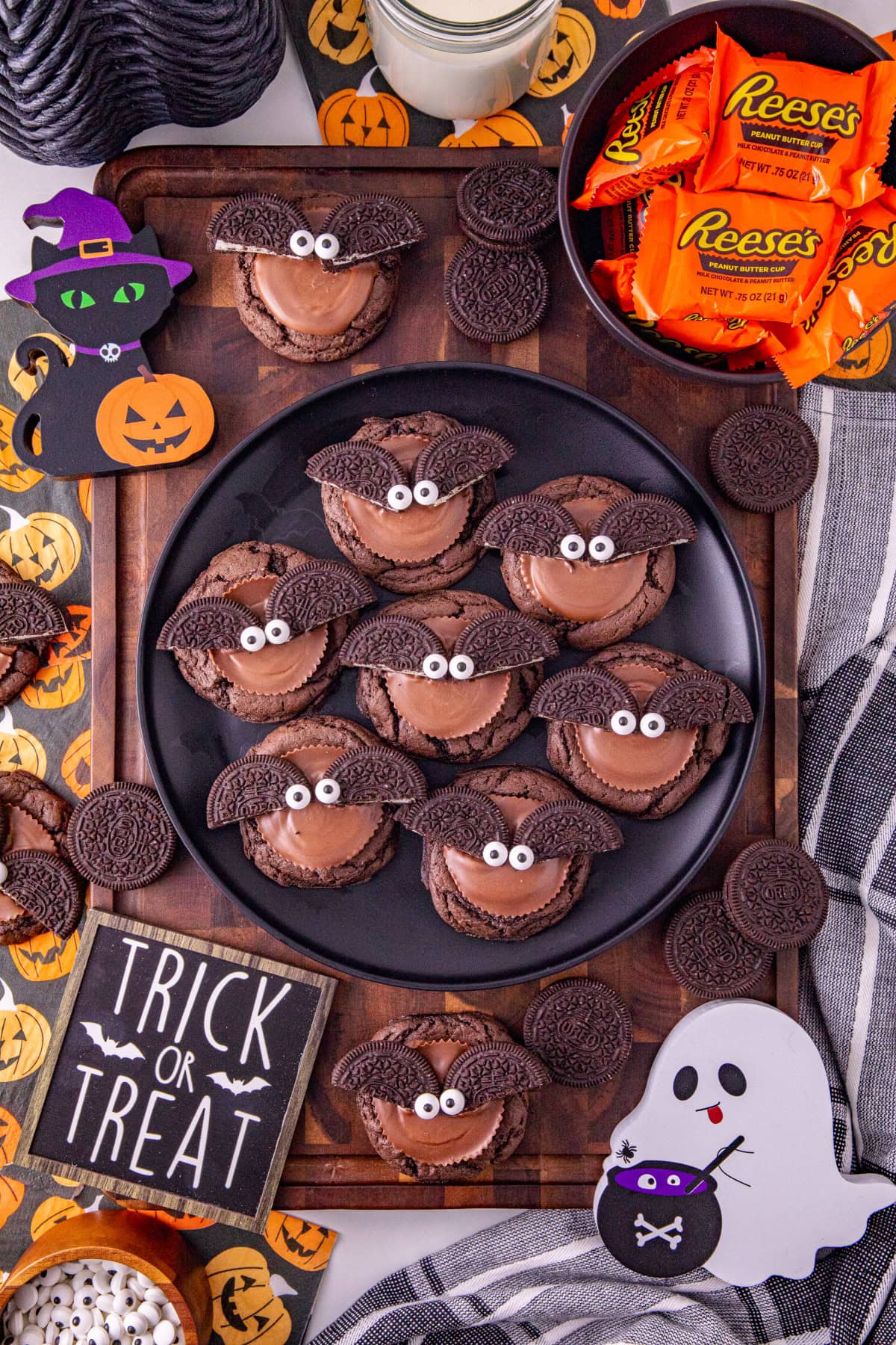 Finished Oreo bat cookies with Reese’s peanut butter cups and candy eyes arranged with Halloween decorations.