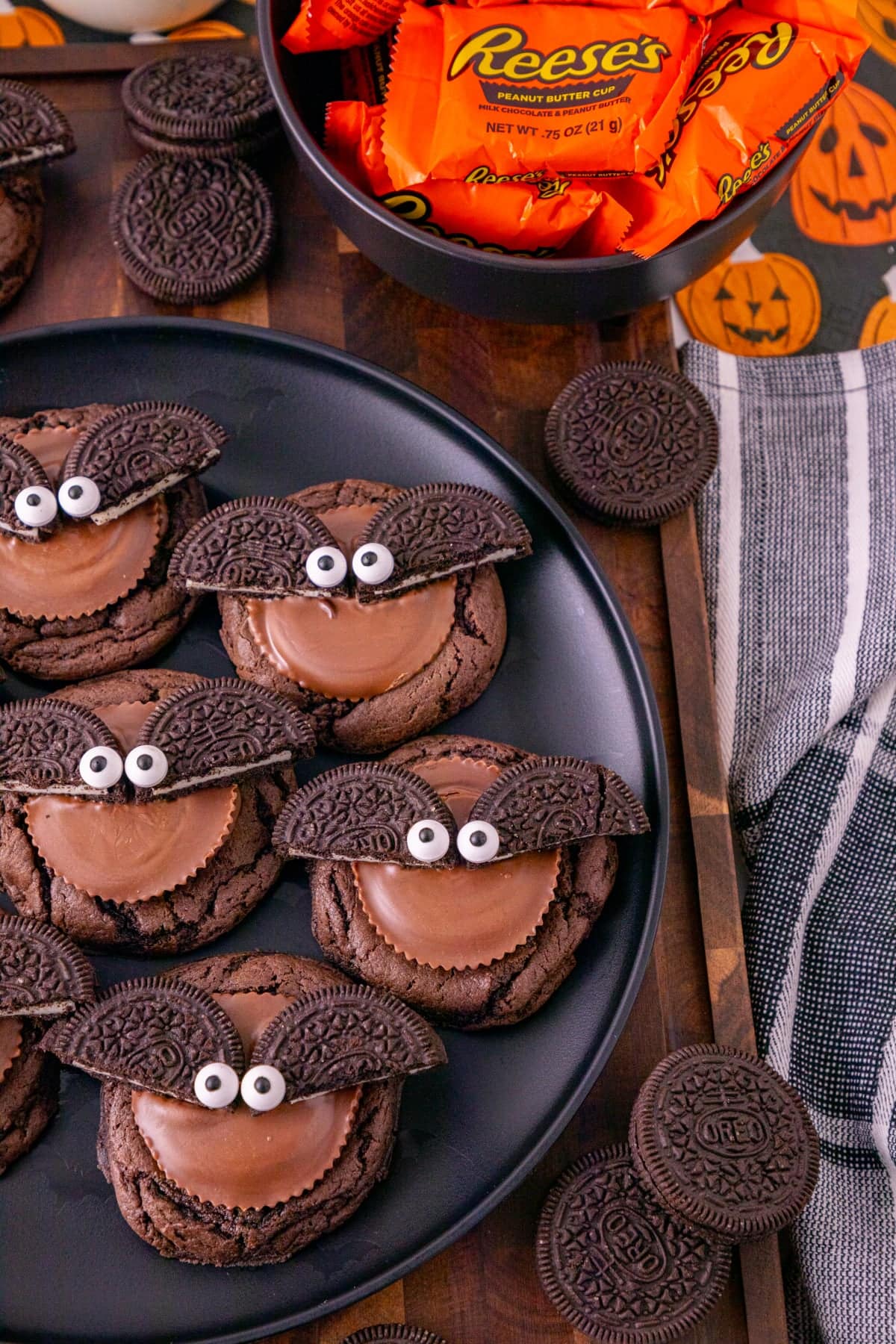 Oreo bat cookies with Reese’s peanut butter cups and candy eyes displayed beside Oreos and Halloween treats.