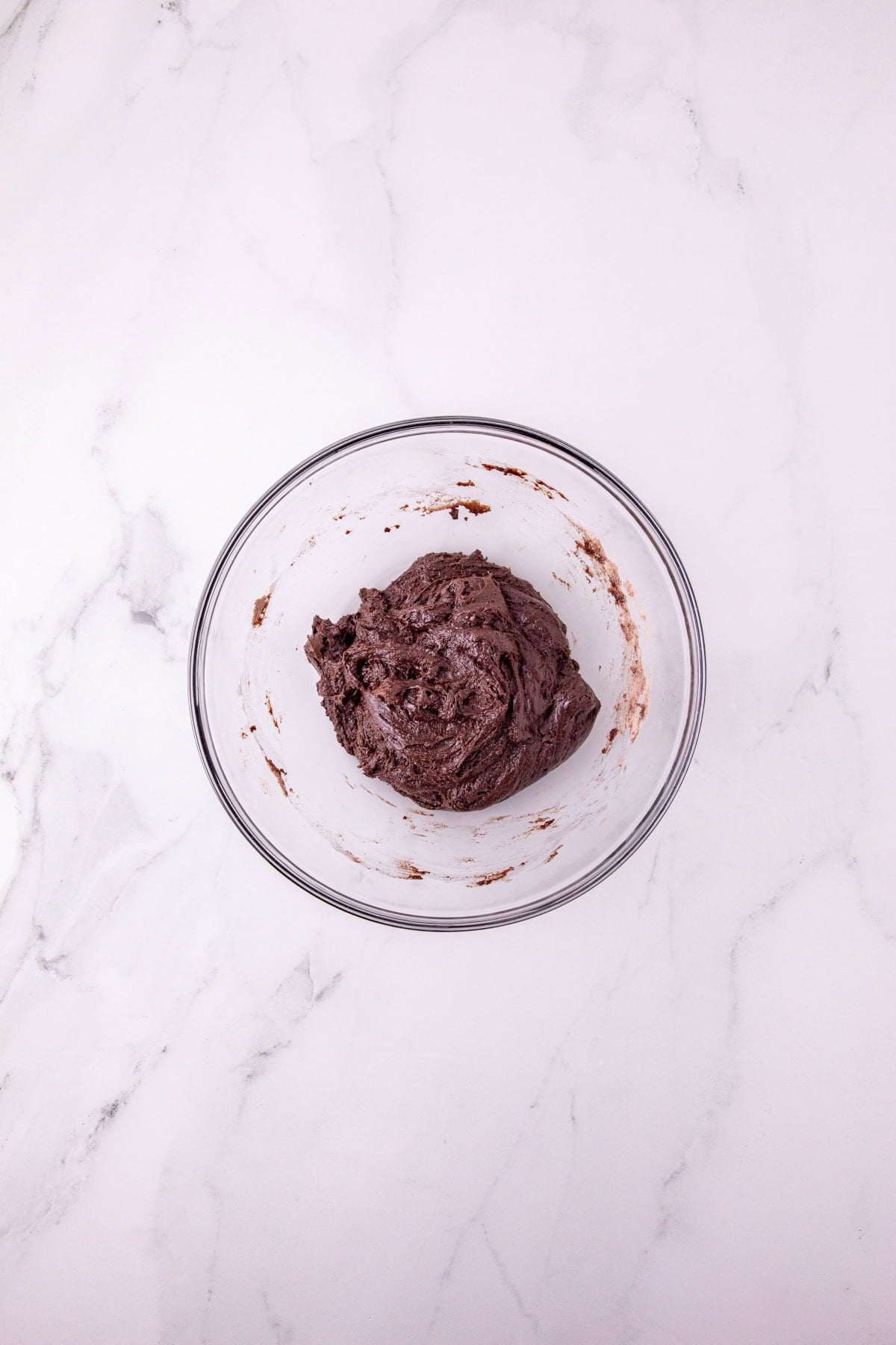 Thick chocolate cookie dough mixed together in a glass bowl.