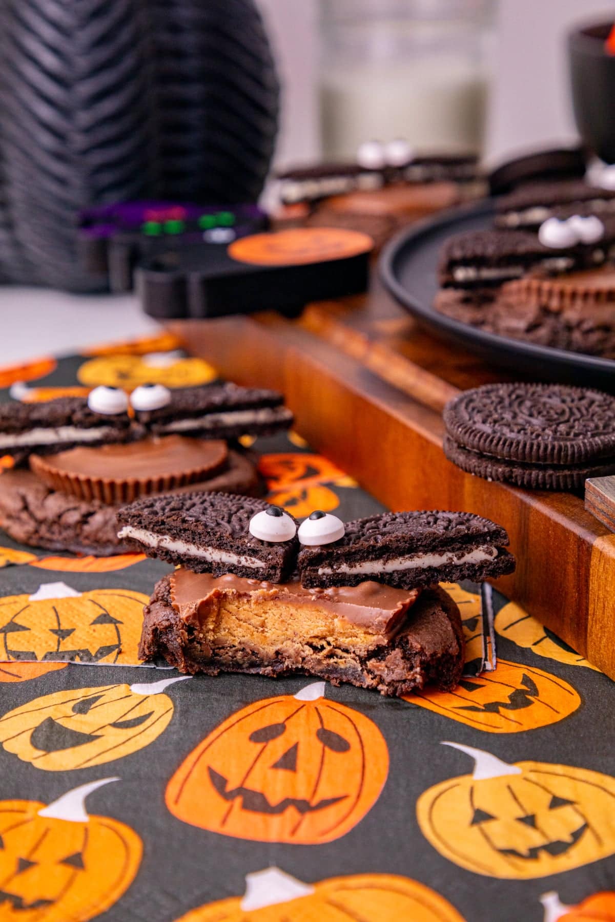 Oreo bat cookies topped with Reese’s peanut butter cups and candy eyes arranged on a Halloween dessert table.