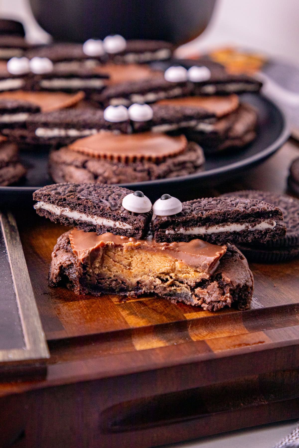 Close-up of a bitten Oreo bat cookie showing the Reese’s peanut butter cup filling, Oreo wings, and candy eyes.