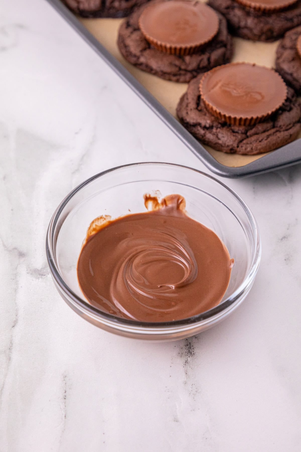 Melted chocolate in a bowl for assembling Oreo bat cookies.