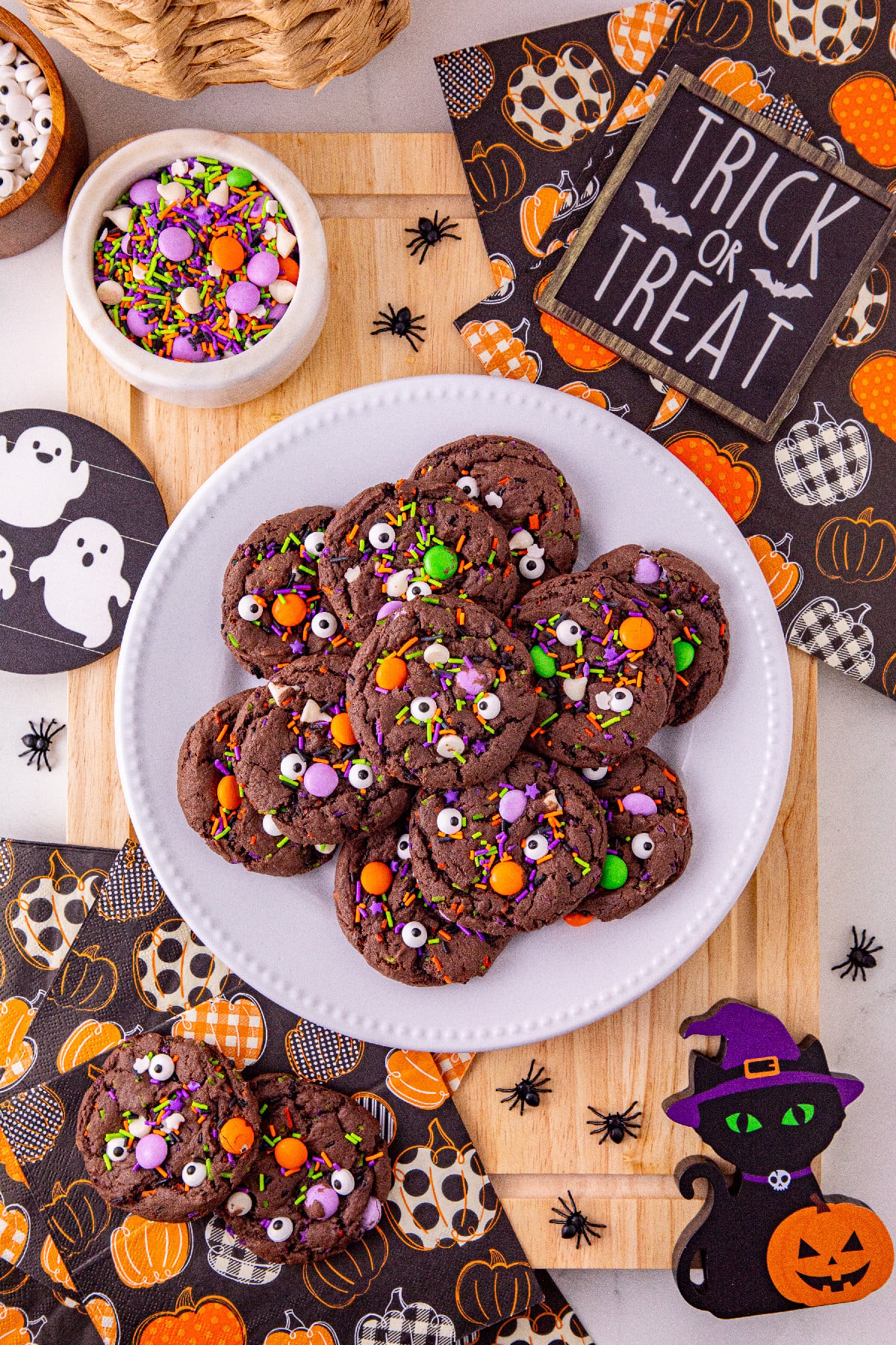 Halloween cake mix cookies with candy eyes and festive sprinkles on a Halloween-themed table.