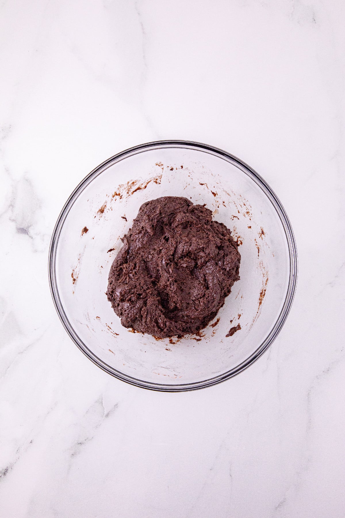 Chocolate cookie dough mixed in a glass bowl.