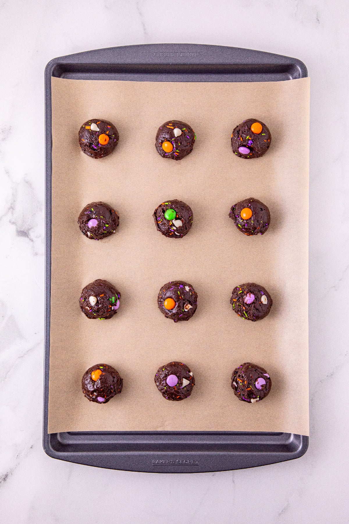 Halloween cake mix cookie dough balls on a parchment-lined baking sheet.
