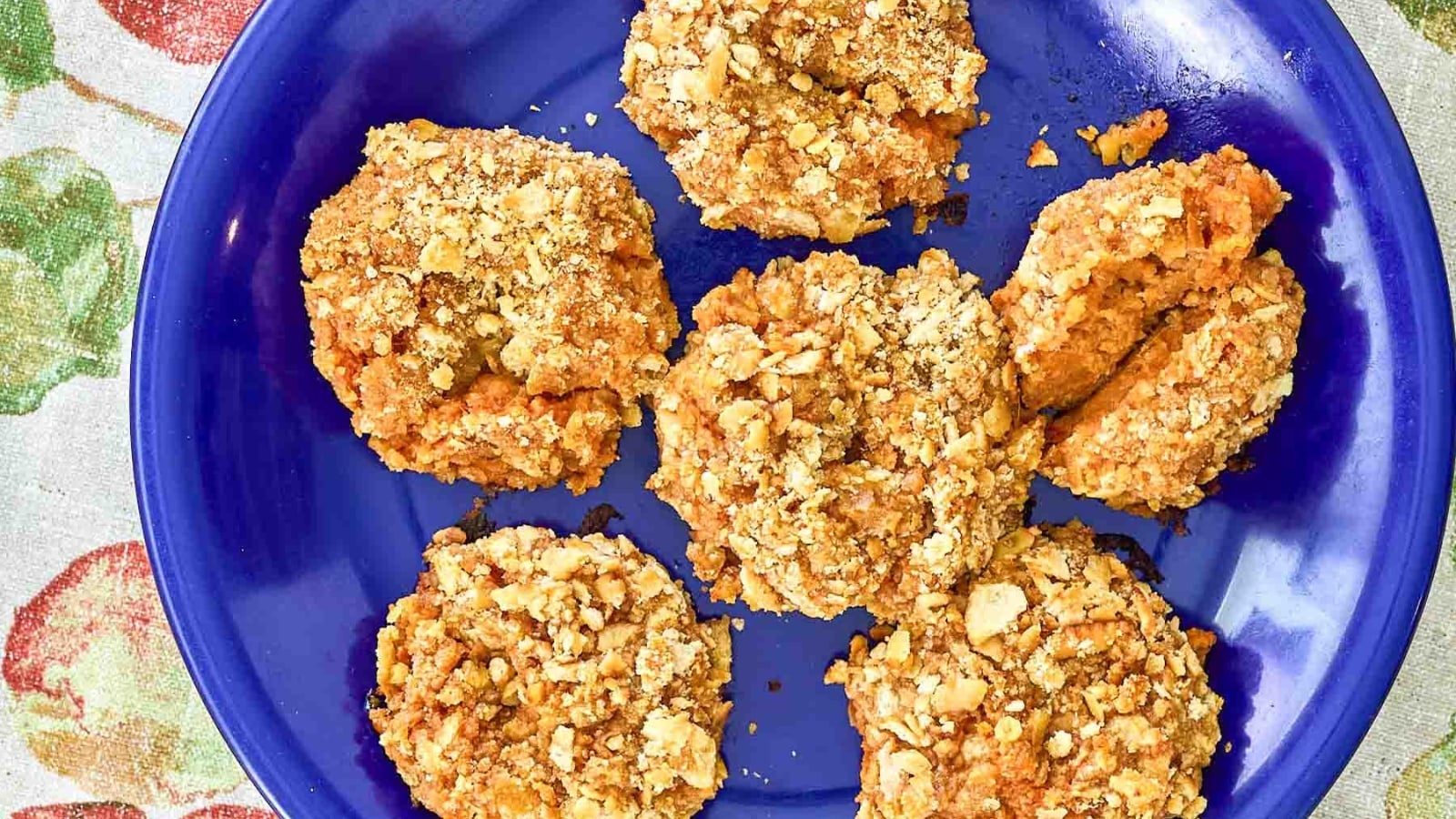 Crispy golden-brown sweet potato puffs coated in crushed cornflakes arranged on a bright blue ceramic plate.