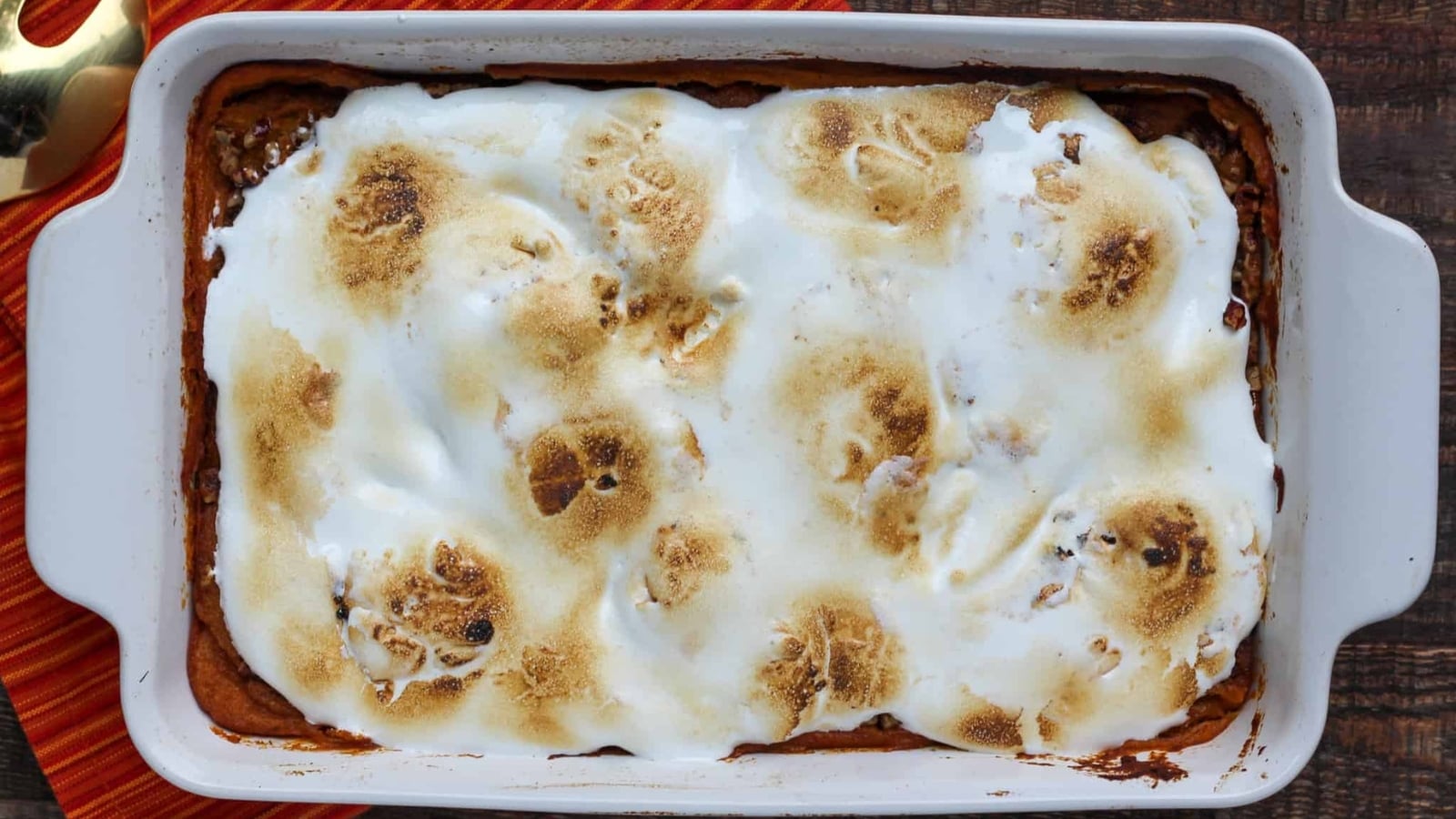 Sweet potato soufflé baked in a white ceramic dish and covered with a layer of toasted, melted marshmallows.